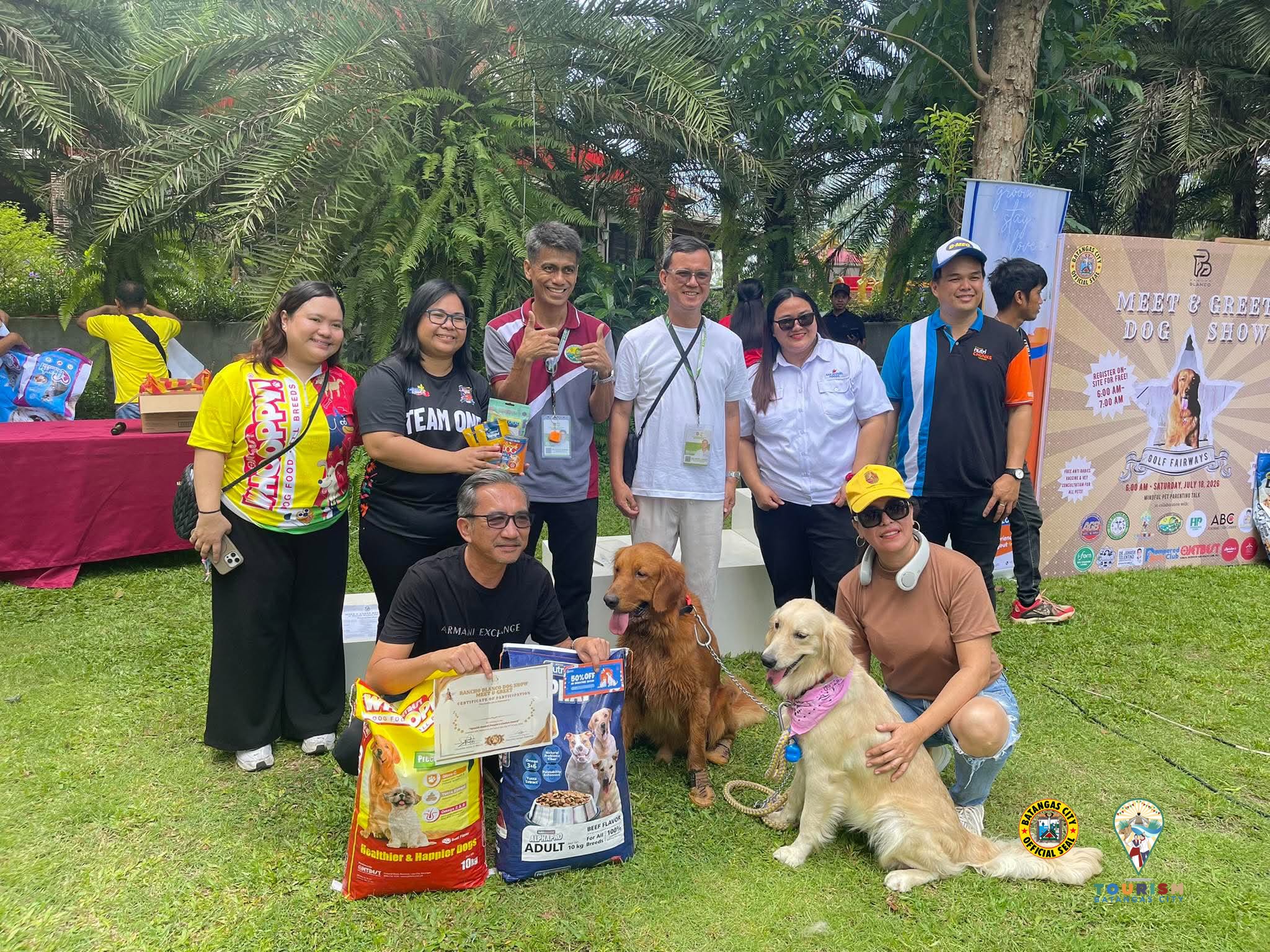 Participants and their golden retrievers in front of the Meet & Greet Dog Show backdrop